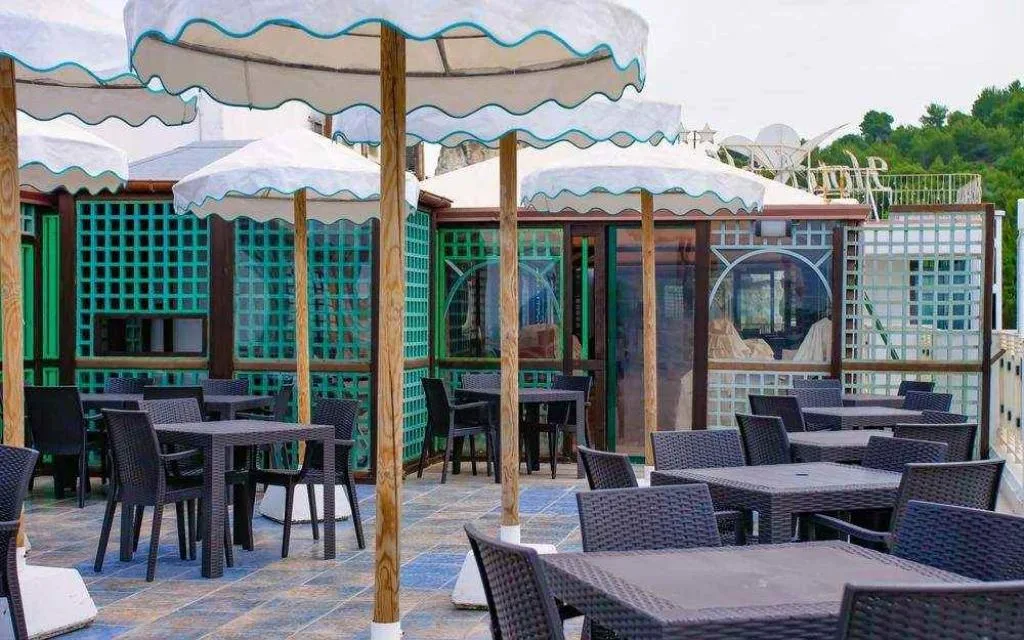 Terrazza esterna con tavoli, sedie in rattan e ombrelloni bianchi