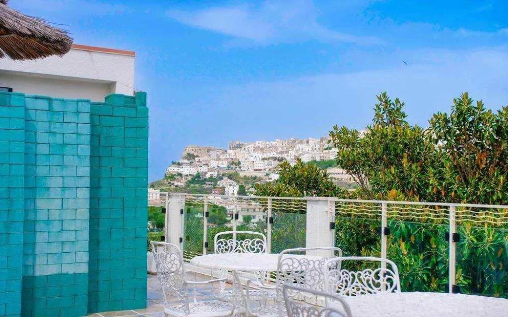Terrazza con tavolo e sedie in ferro battuto bianco e vista sul borgo collinare