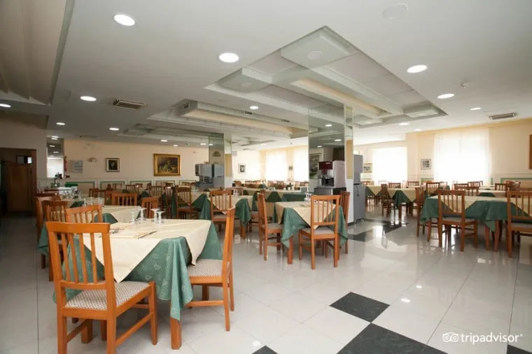 Sala ristorante interna con tavoli apparecchiati e tovaglie verdi