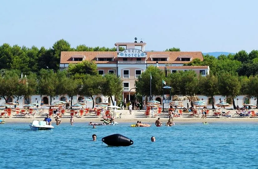 Hotel sulla spiaggia visto dal mare con ombrelloni e bagnanti