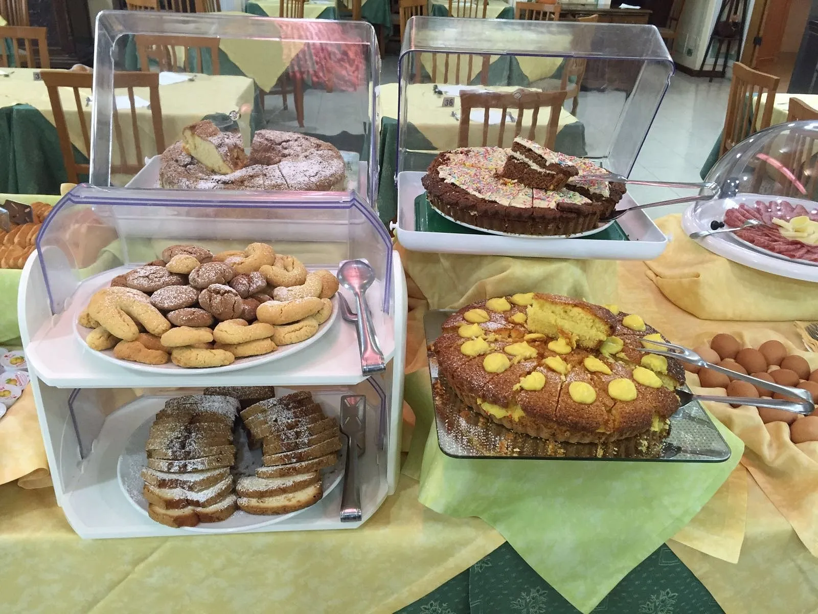 Buffet della colazione con torte, biscotti e affettati su tavolo apparecchiato