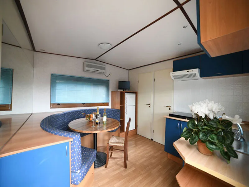 Interno di mobile home con angolo pranzo blu, tavolo e cucina moderna