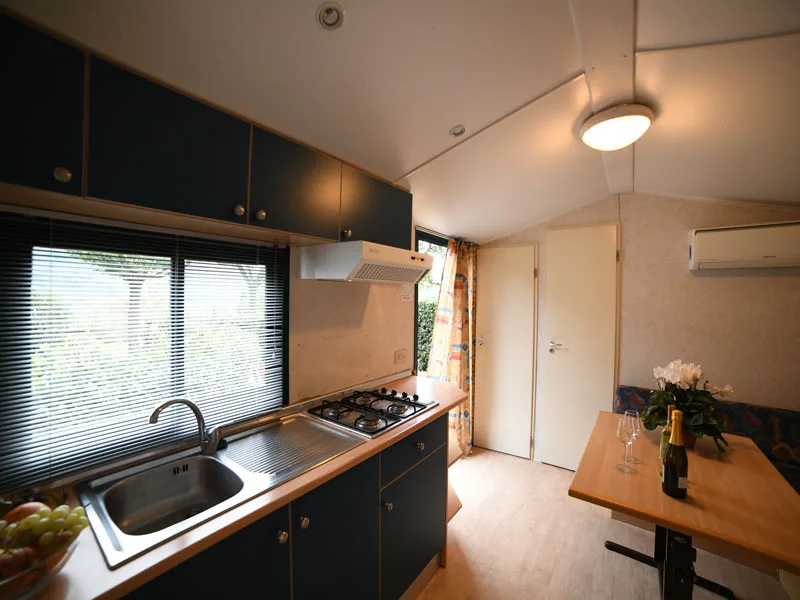 Cucina di mobile home con mobili blu, piano cottura e angolo pranzo