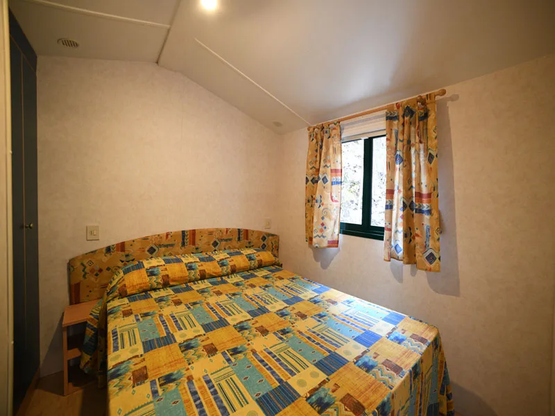 Camera da letto matrimoniale con copriletto colorato e finestra con tende