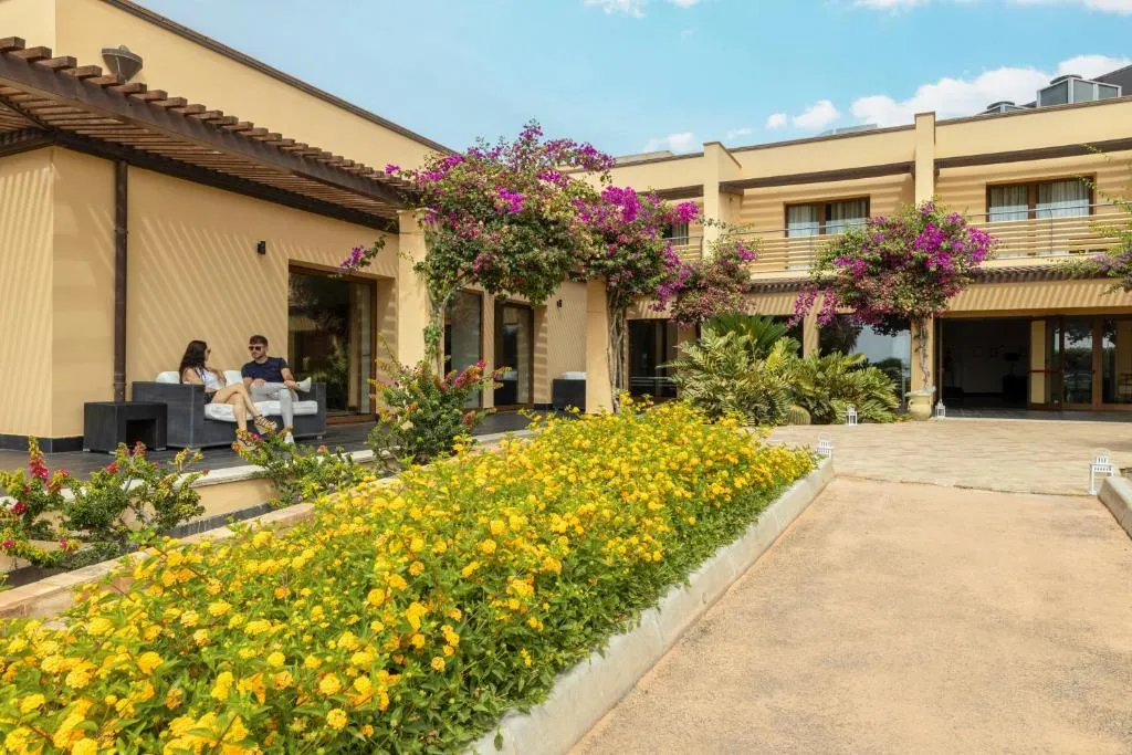 Esterno dell'hotel con giardino fiorito, bouganville e area lounge all'aperto