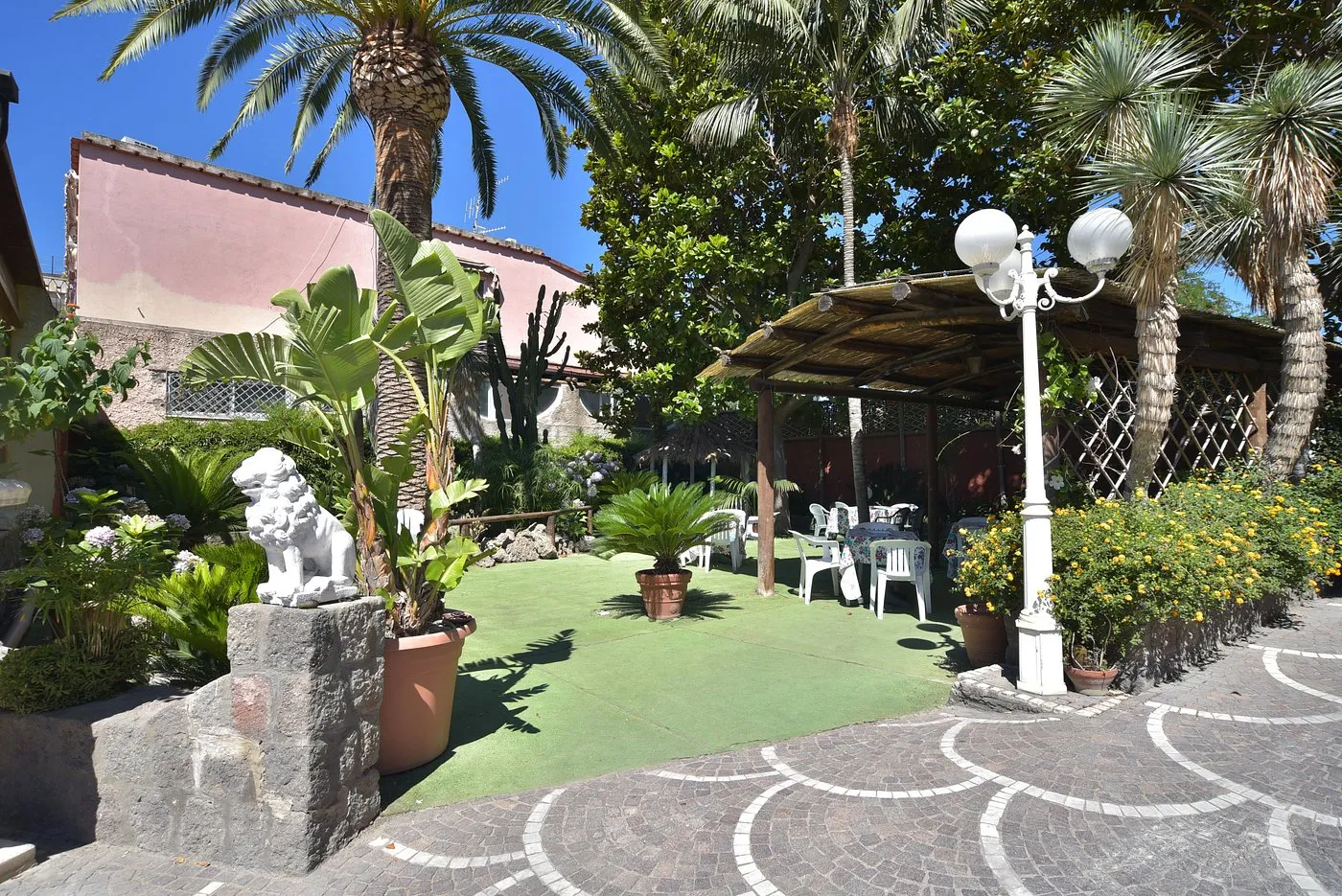 Giardino dell'hotel con palme, gazebo in paglia e area relax