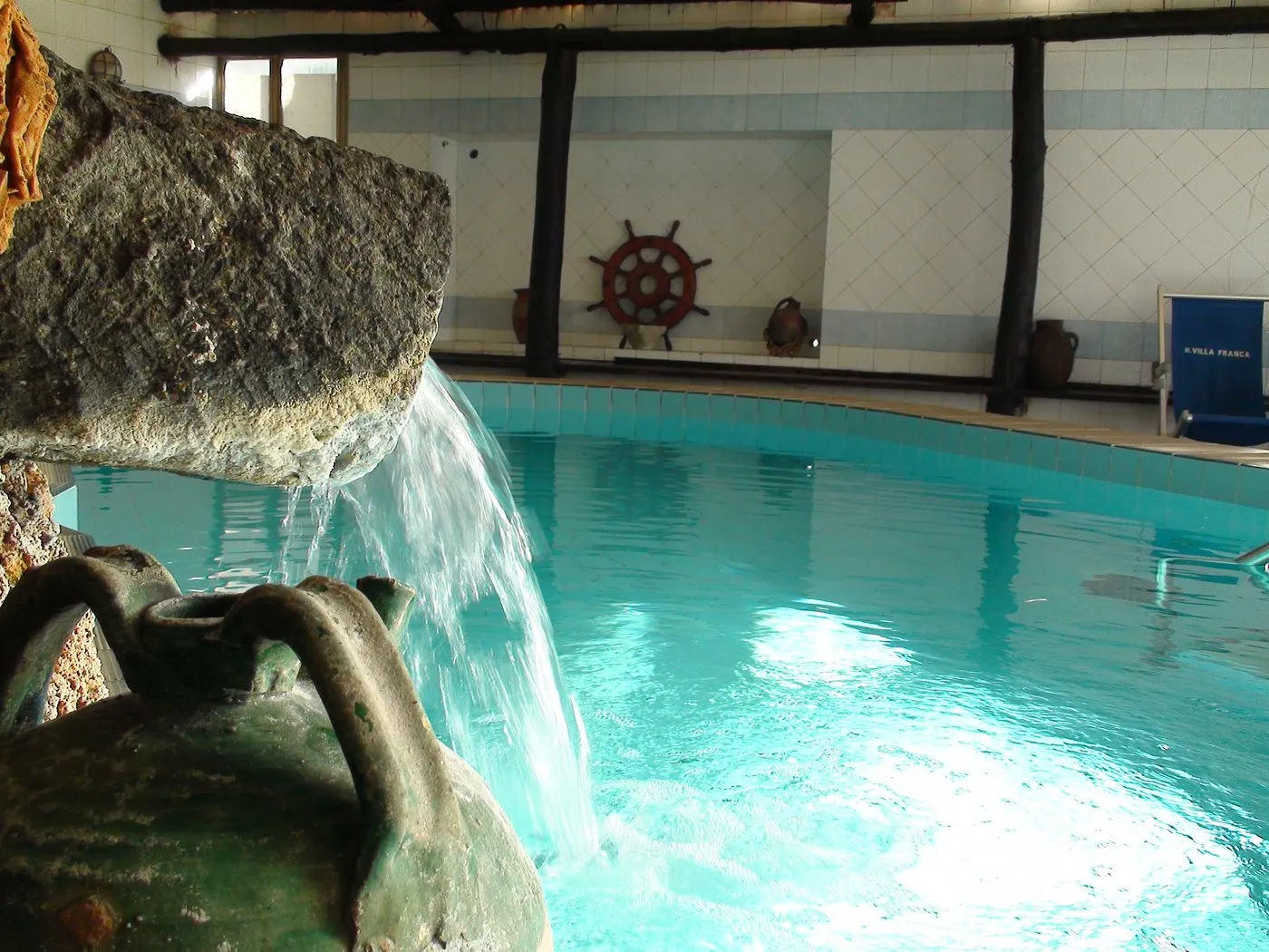 Piscina interna termale con cascata d'acqua e decorazioni marine