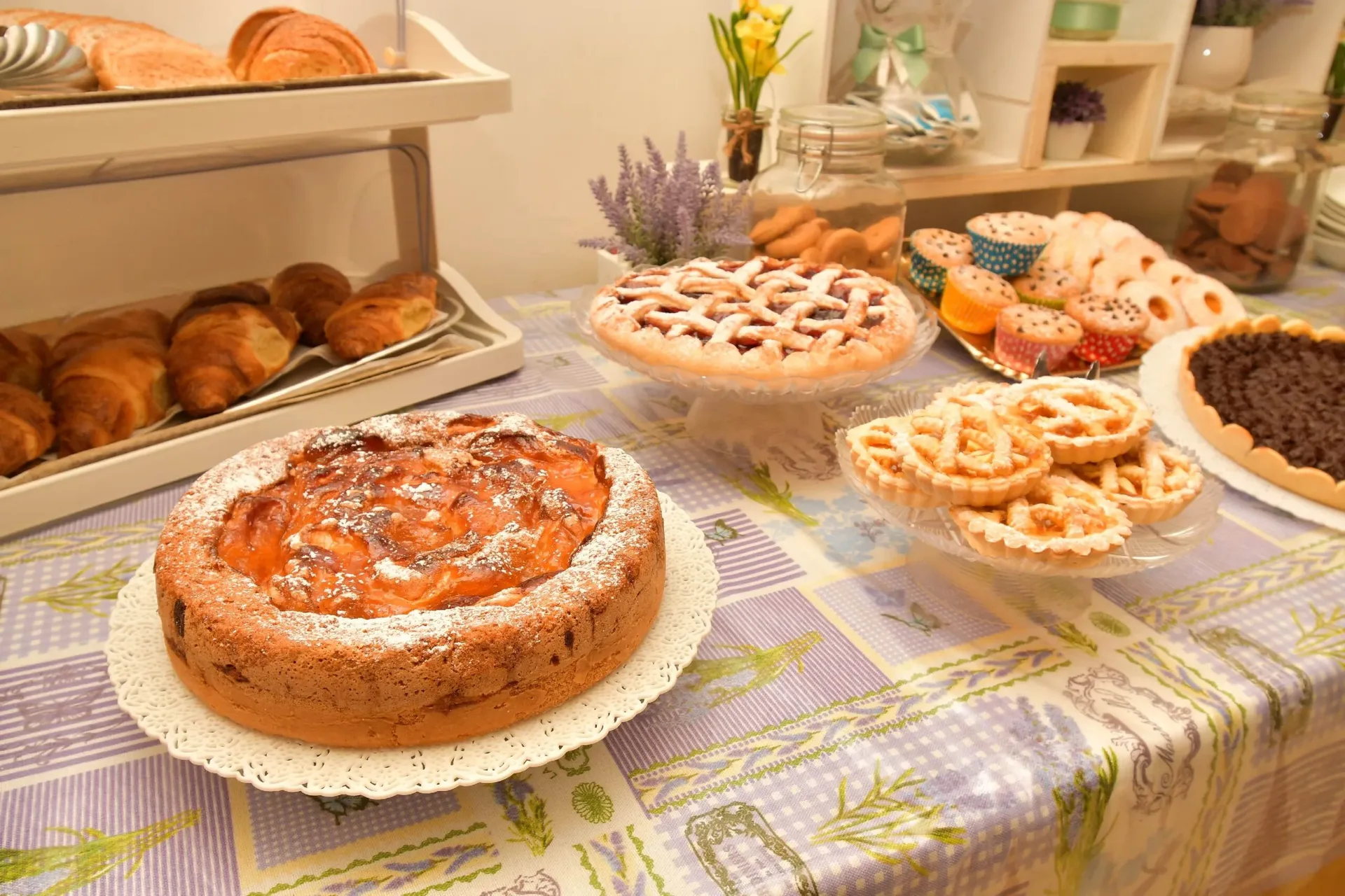 Tavolo della colazione con torte fatte in casa, crostate e cornetti