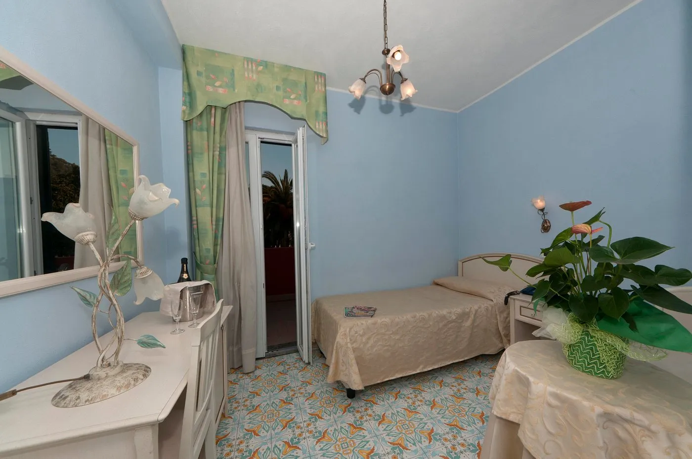 Camera azzurra con letto singolo, balcone e pavimento in maiolica