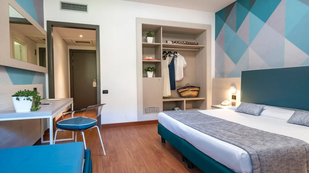 Camera moderna con letto matrimoniale, scrivania e parete decorata