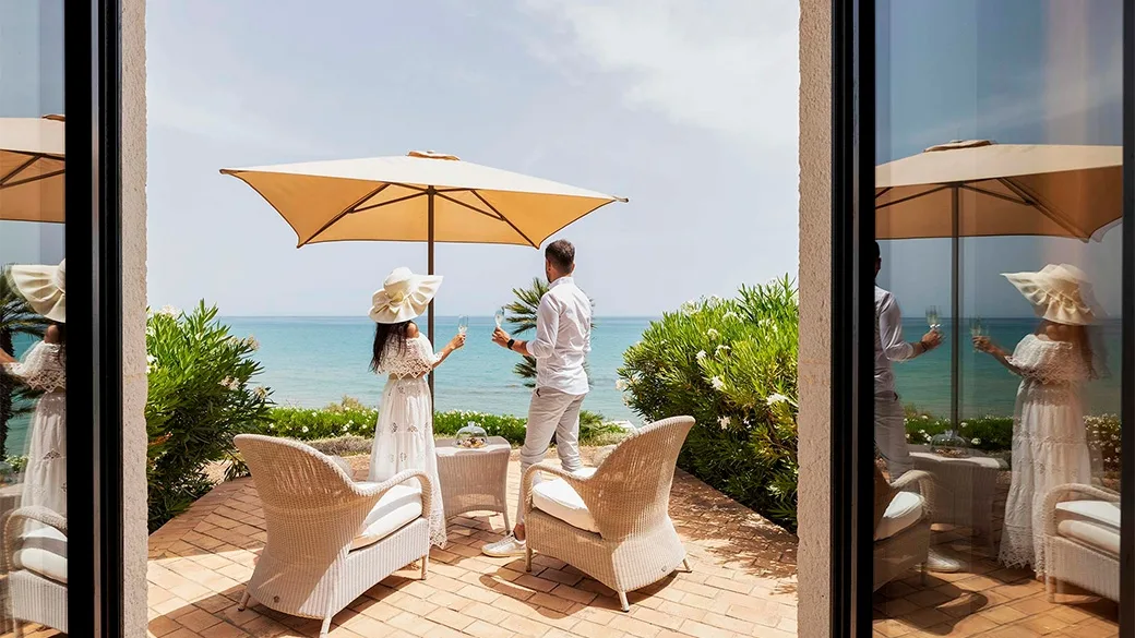 Terrazza privata con ombrellone e poltrone in vimini affacciata sul mare