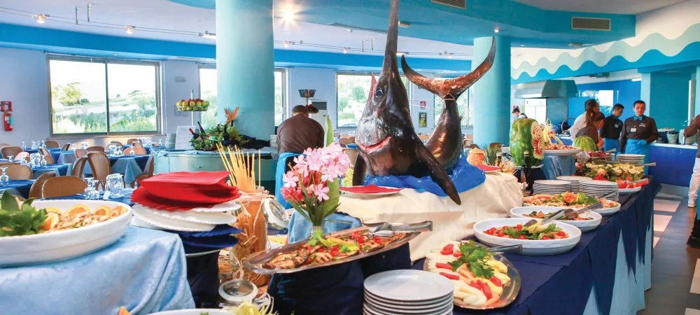 Ricco buffet del ristorante con pesce spada decorativo, piatti di pesce e antipasti in sala dai toni blu