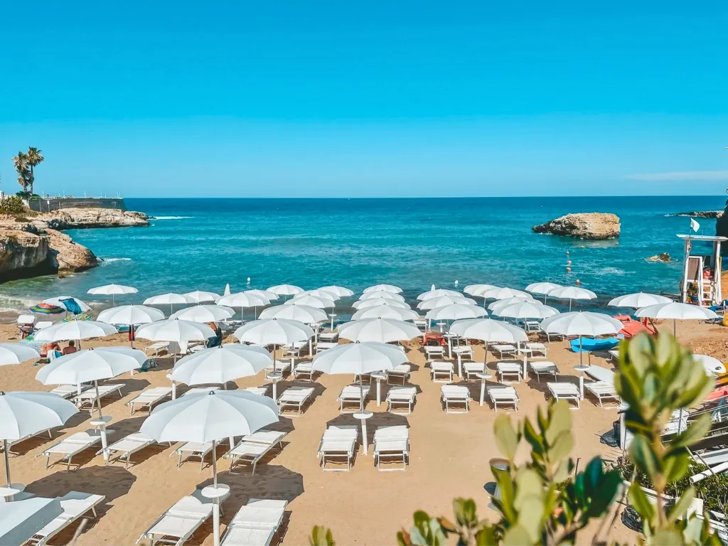 Spiaggia con ombrelloni e lettini bianchi affacciata sul mare turchese