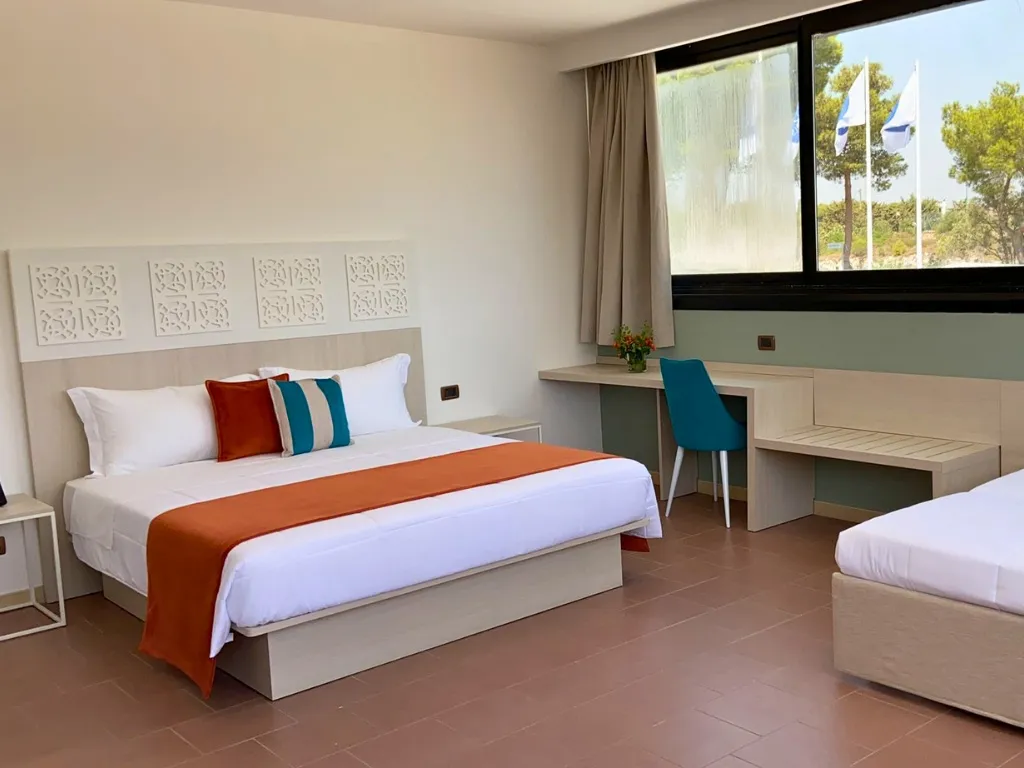 Camera spaziosa con letto matrimoniale e letto singolo, scrivania e vista sulle bandiere