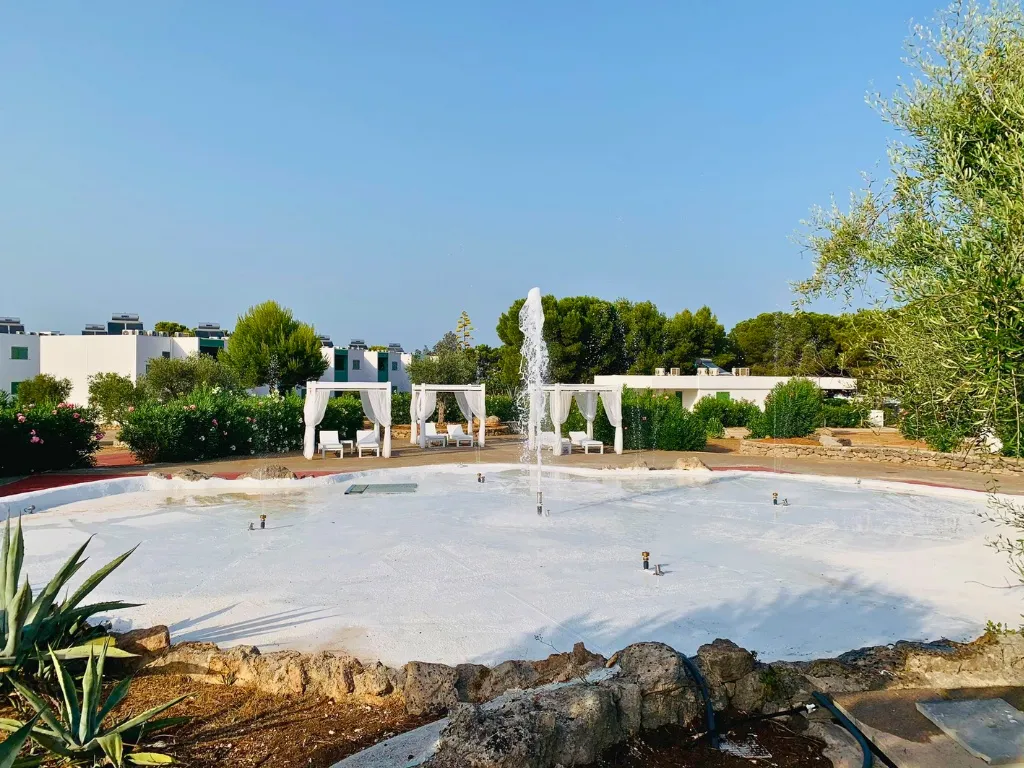 Fontana giocosa con getto d'acqua e gazebo bianchi in un'area giardino del resort