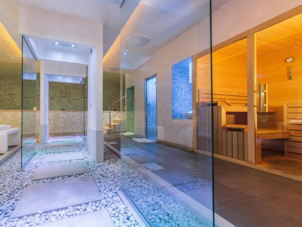 Zona spa con percorso a ciottoli, sauna in legno e illuminazione soffusa