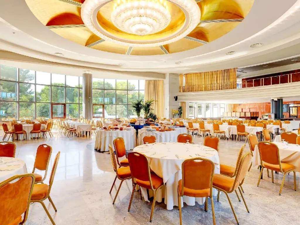 Sala ristorante elegante con lampadario dorato, tavoli rotondi e grandi vetrate