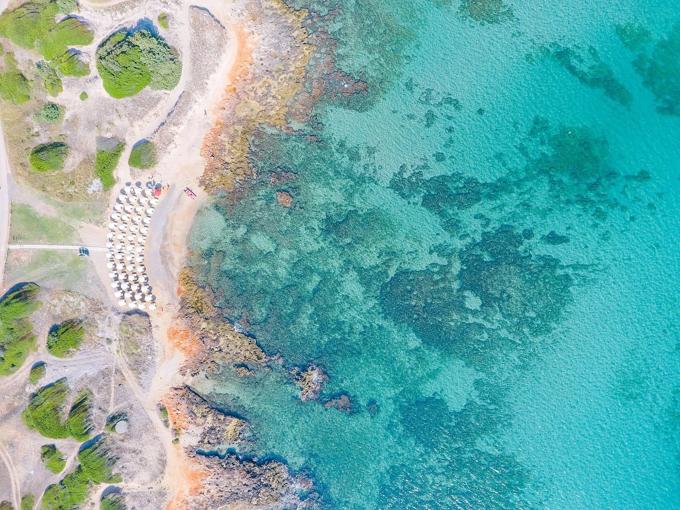 Vista aerea della costa con acqua cristallina turchese e spiaggia con ombrelloni