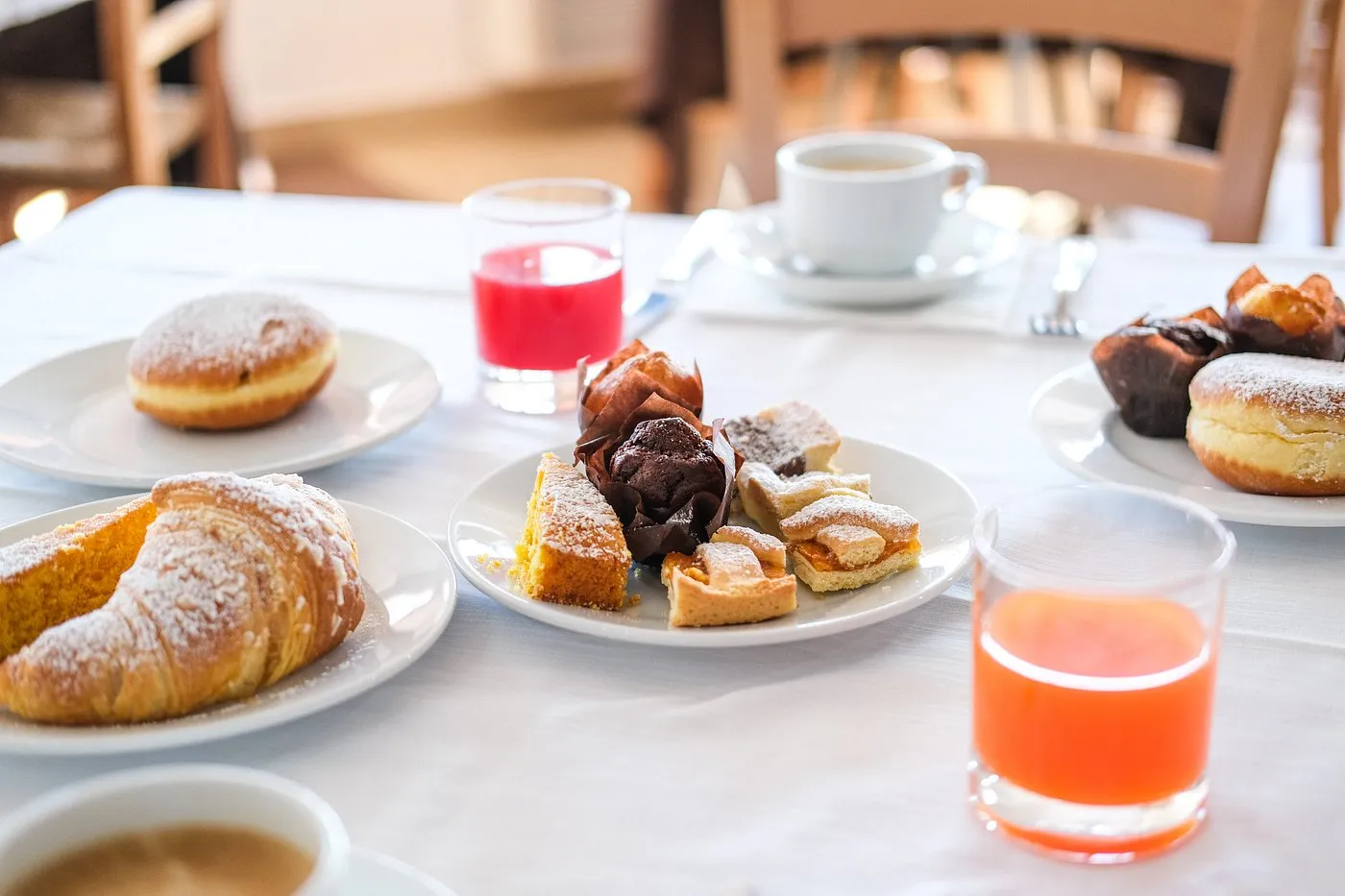 Colazione italiana con cornetti, dolci, caffè e succhi di frutta