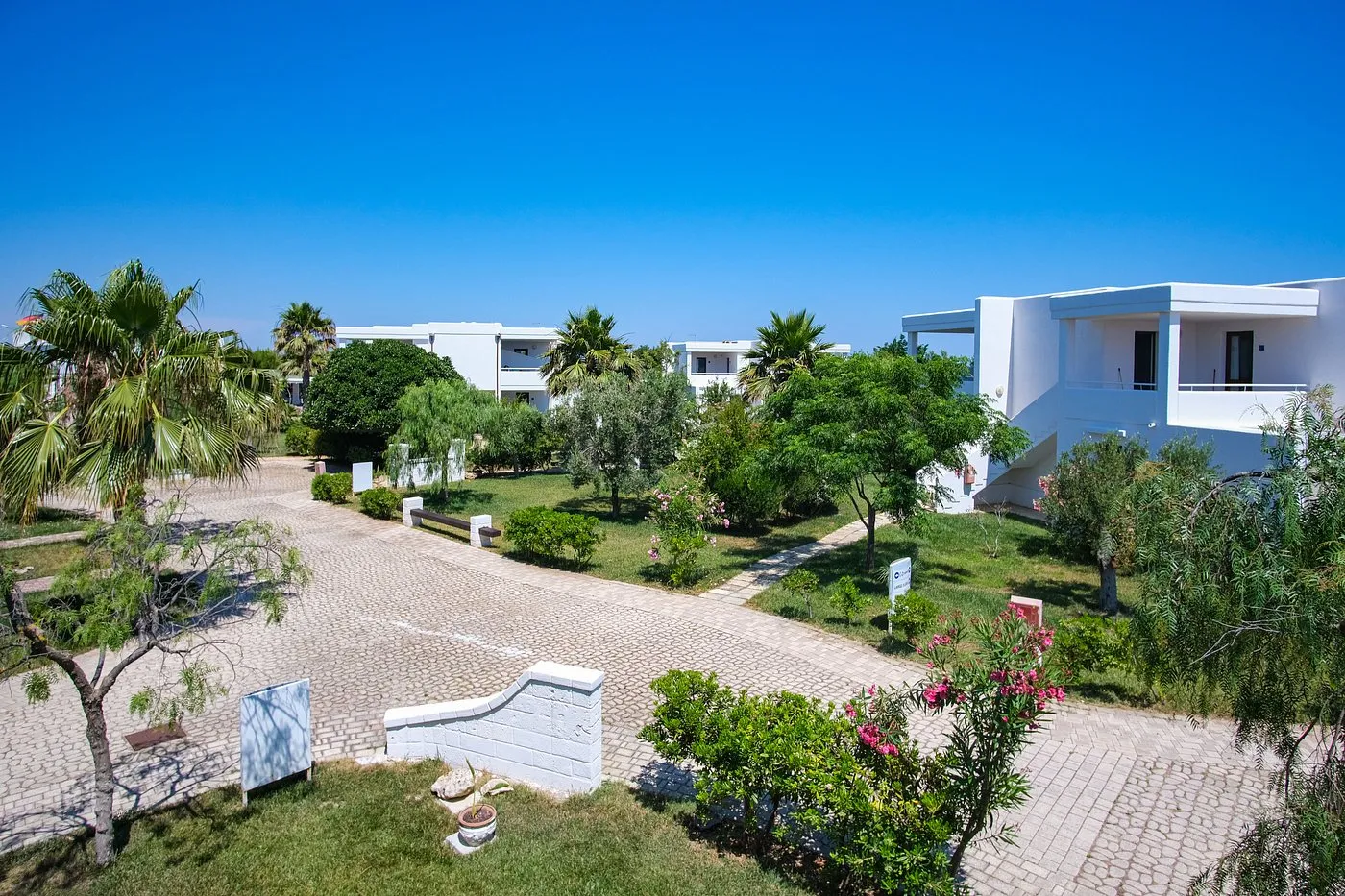 Viale interno del resort con giardini curati e ville bianche