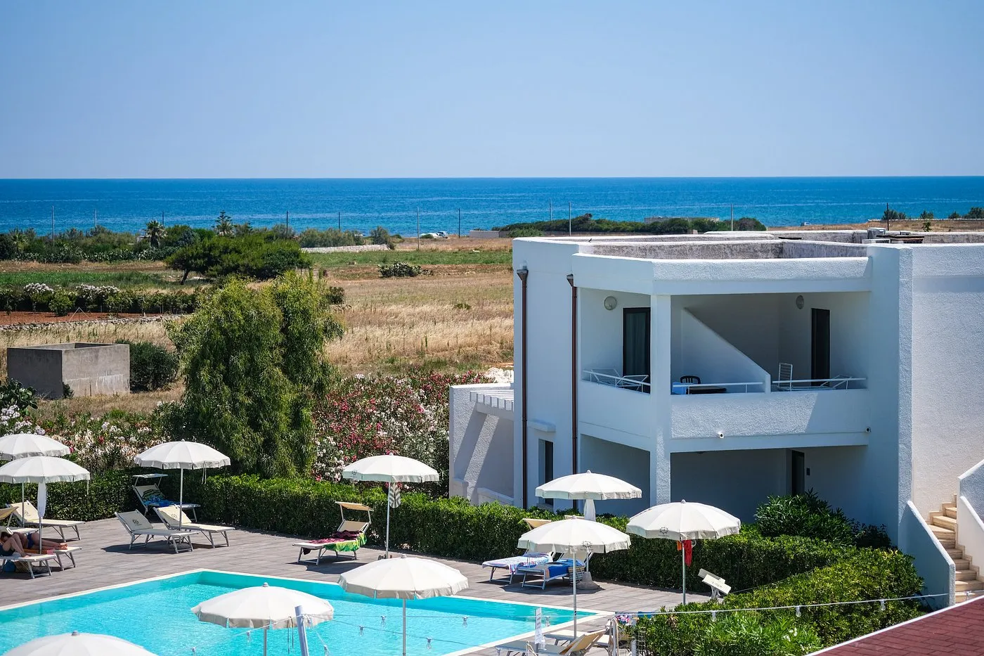 Edificio bianco del resort con piscina in primo piano e vista sul mare