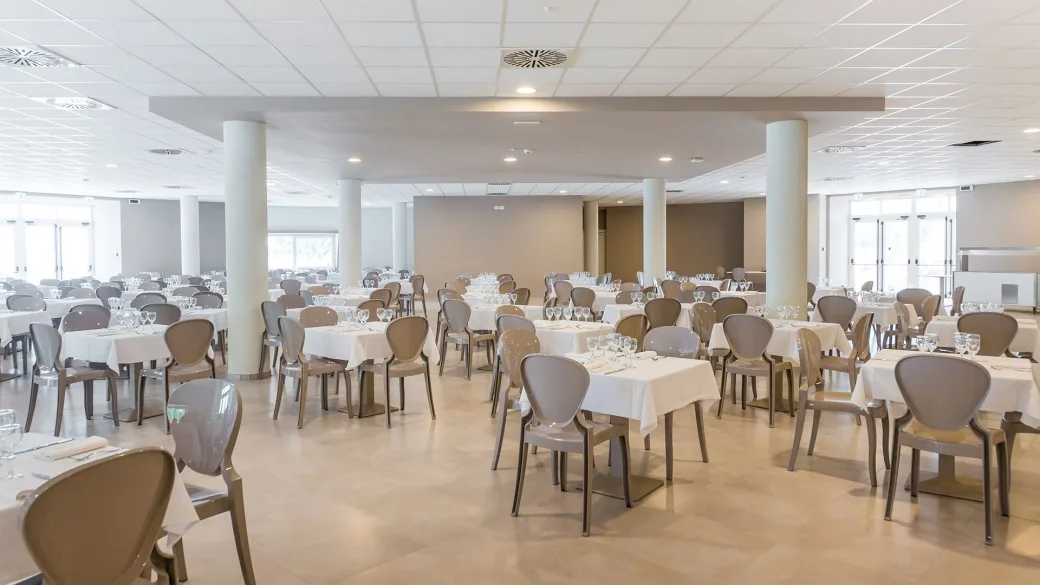 Ampia sala ristorante luminosa con tavoli apparecchiati e sedie moderne