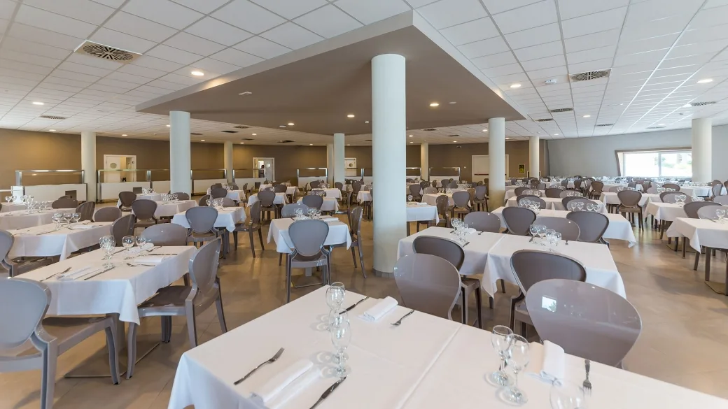 Sala ristorante interna con numerosi tavoli apparecchiati e colonne bianche