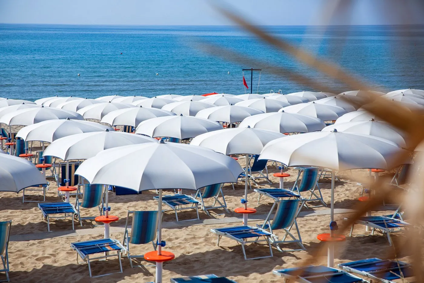 Ombrelloni bianchi e lettini blu sulla sabbia con vista sul mare