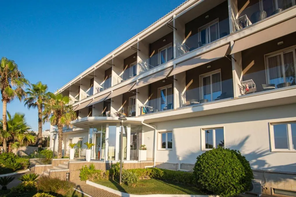 Facciata dell'hotel con balconi, palme e ingresso vetrato