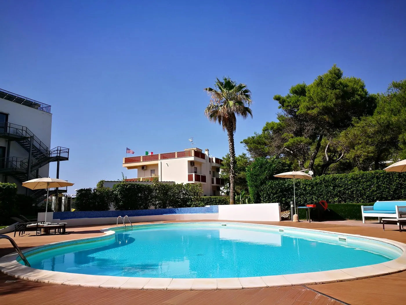 Piscina all'aperto con palma e cielo azzurro tra gli edifici