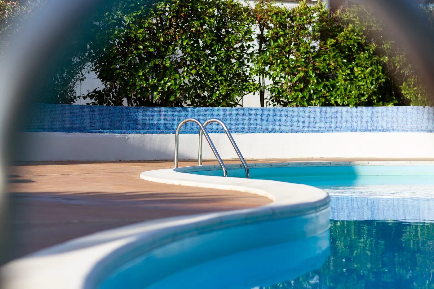 Dettaglio del bordo piscina con scaletta in acciaio e mosaico azzurro