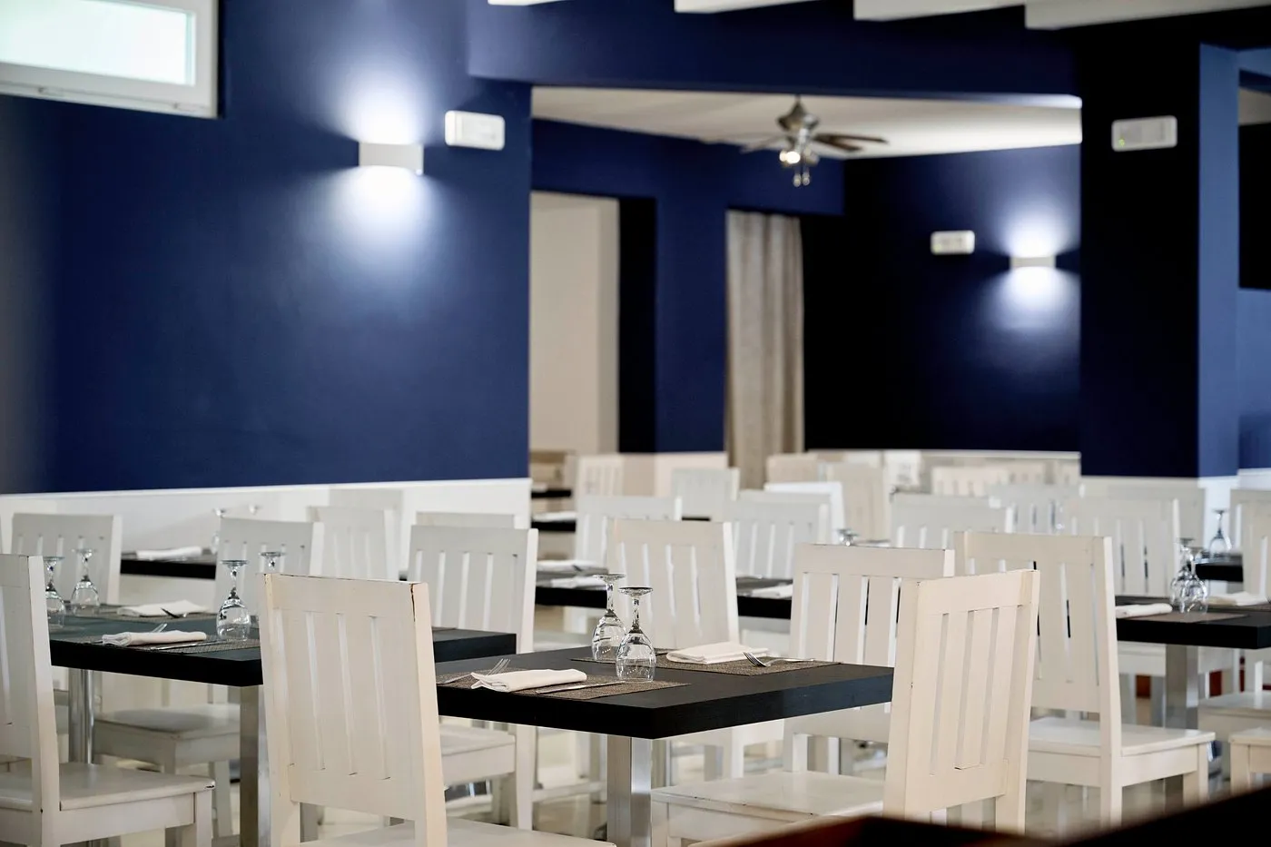 Sala da pranzo elegante con tavoli scuri e sedie bianche