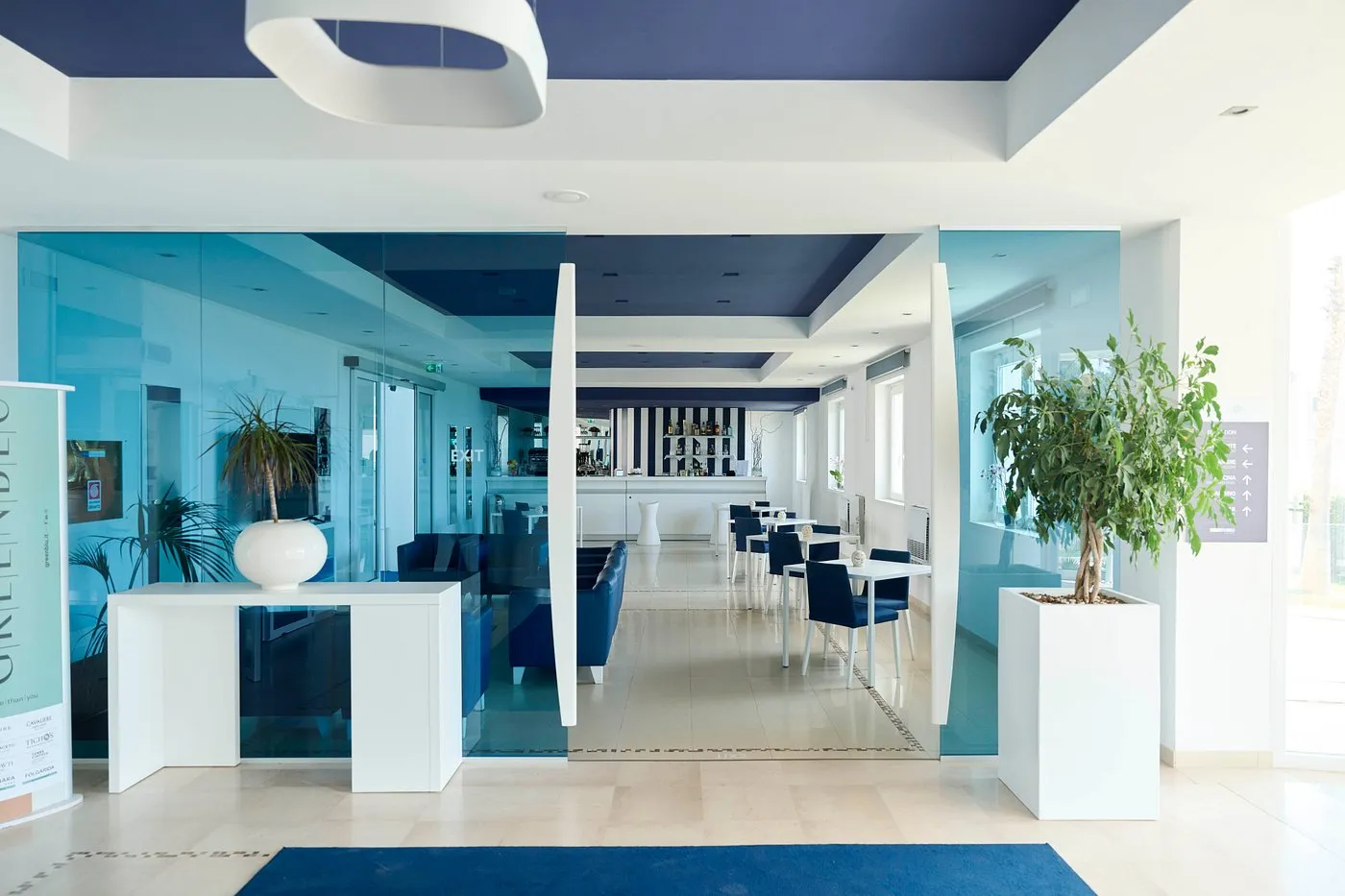 Ingresso dell'hotel con pareti in vetro azzurro e zona bar