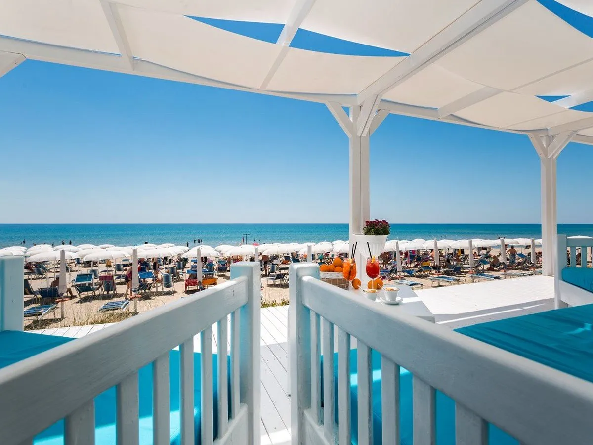 Terrazza bianca con vista sulla spiaggia attrezzata e aperitivi