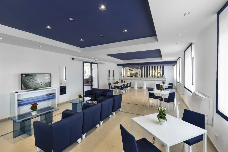 Area lounge con divani blu, tavoli bianchi e bar