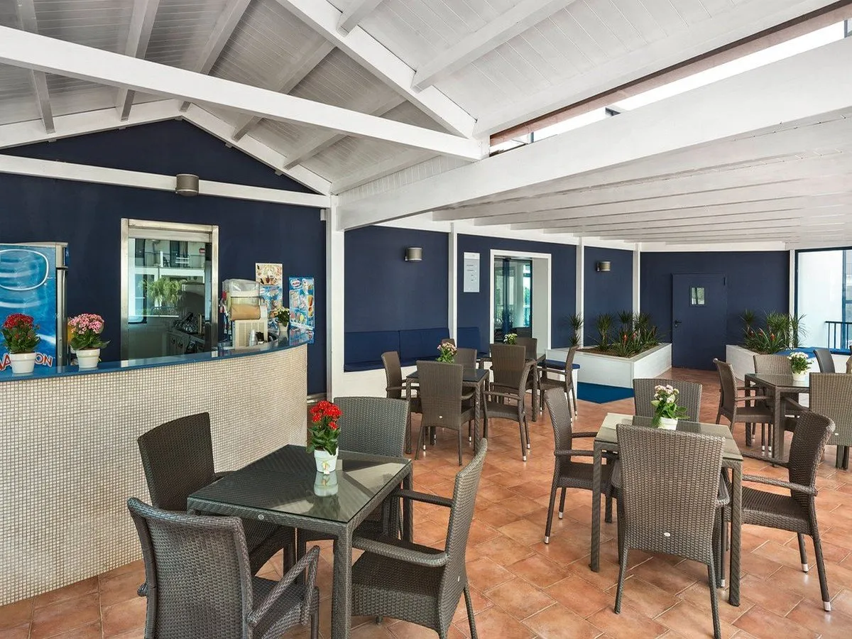 Bar con tavoli in rattan e pareti blu sotto tetto in legno bianco