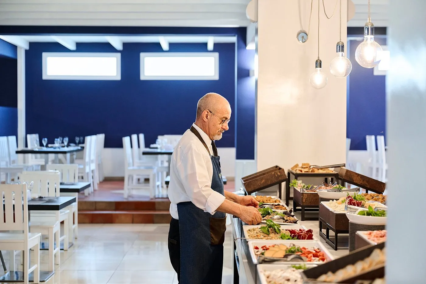 Cameriere prepara il buffet nella sala ristorante