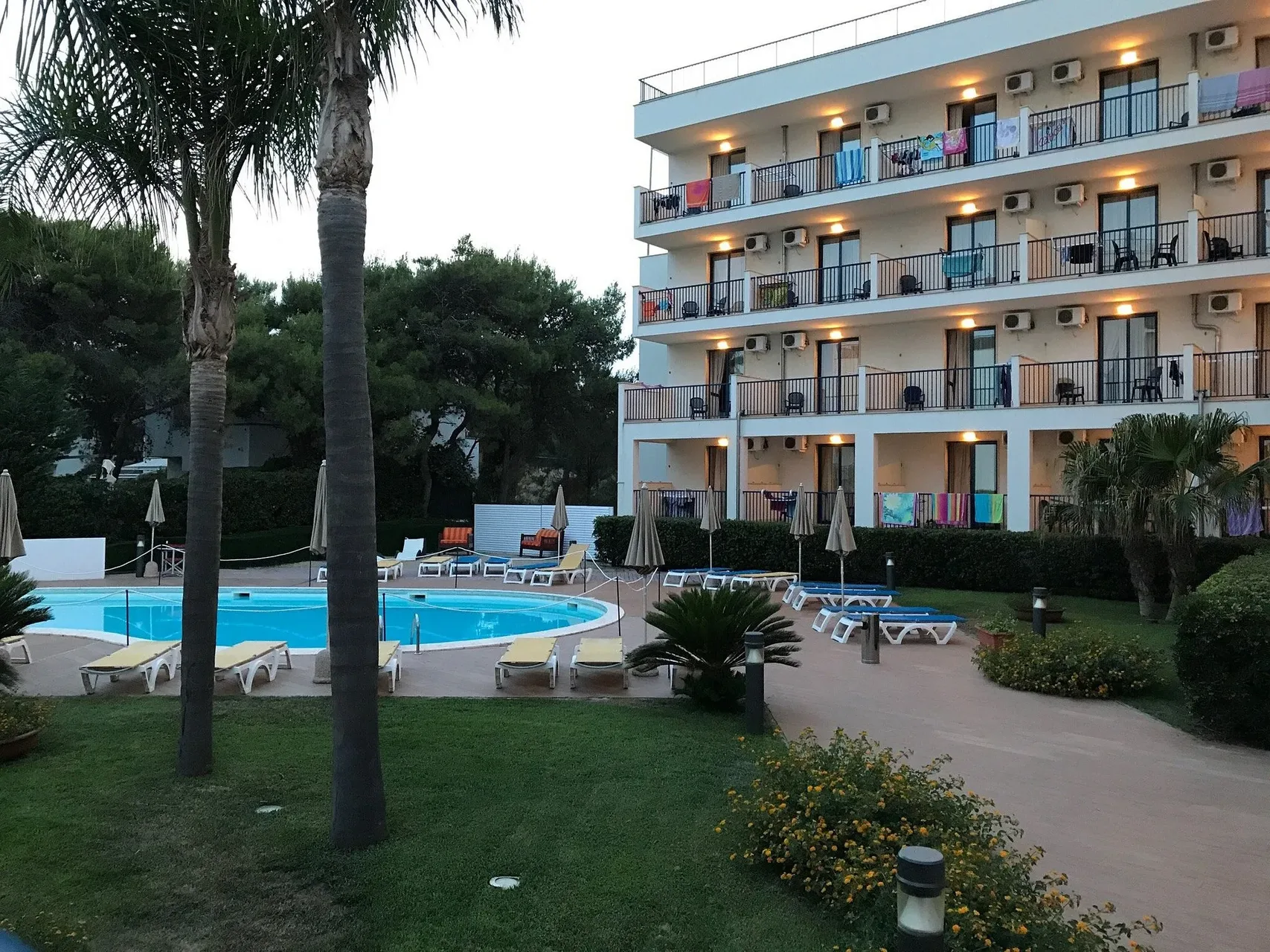Piscina e giardino dell'hotel al crepuscolo con balconi illuminati