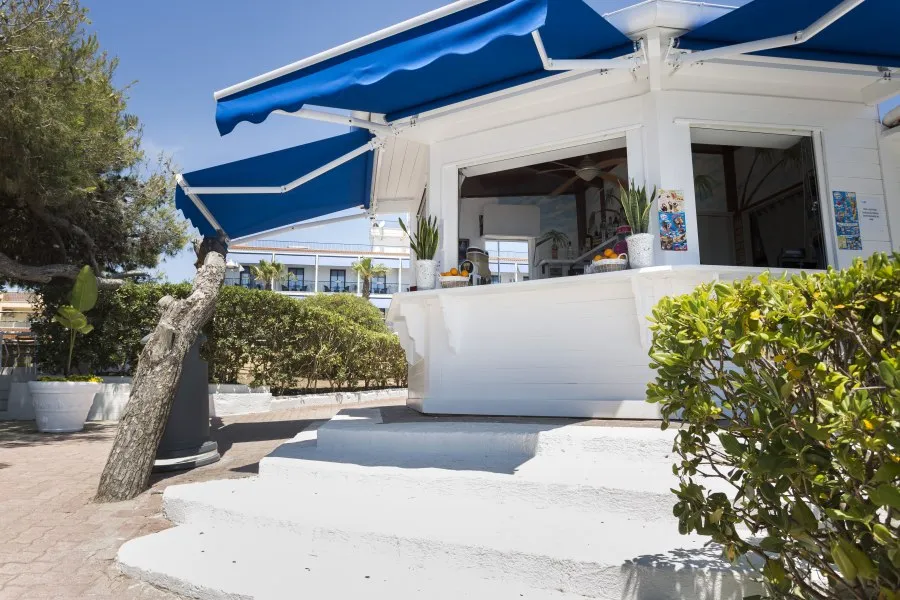Chiosco bar in spiaggia con tenda blu e piante verdi