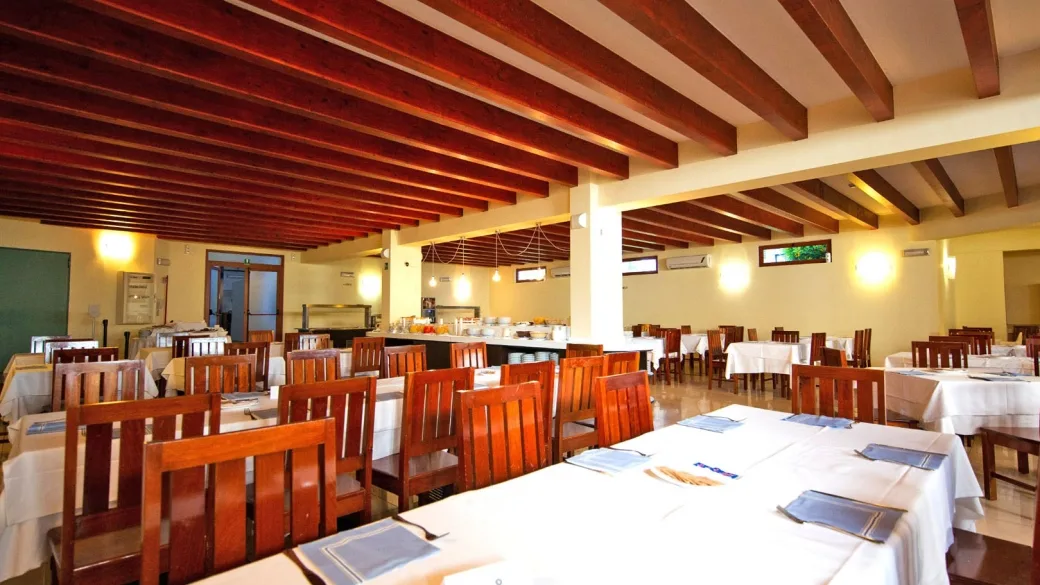 Sala ristorante interna con travi in legno e tavoli apparecchiati