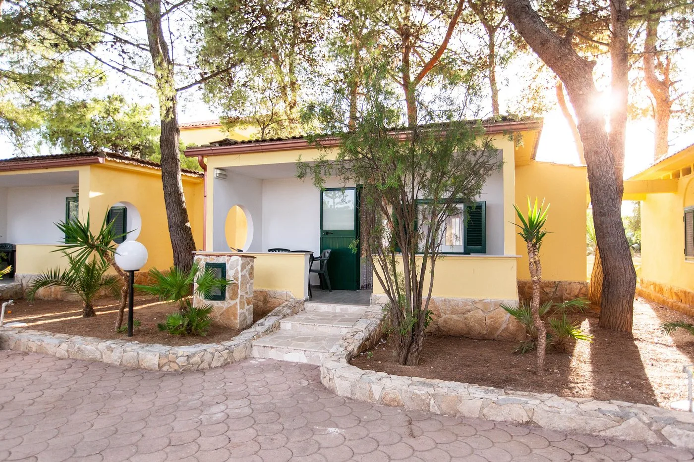Villetta gialla con veranda e giardino tra i pini nel villaggio