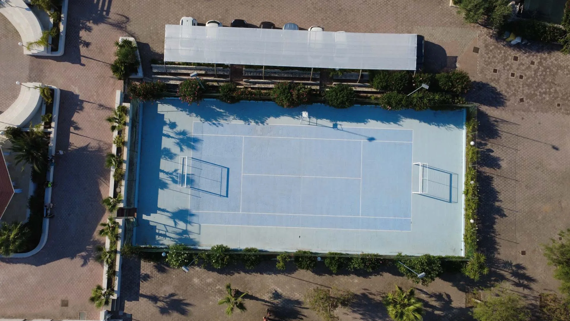 Vista aerea del campo da tennis circondato da palme e vegetazione
