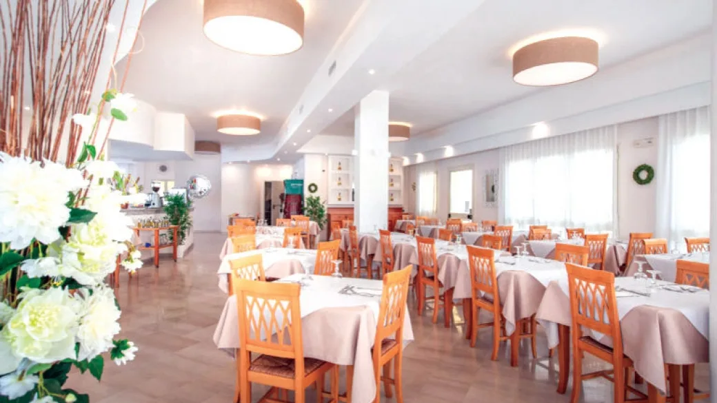 Sala ristorante con tavoli apparecchiati e sedie in legno arancione