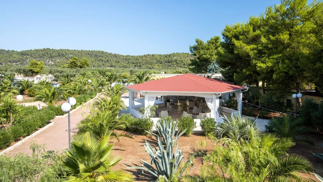 Gazebo con tetto rosso e salotti immerso nel giardino tropicale