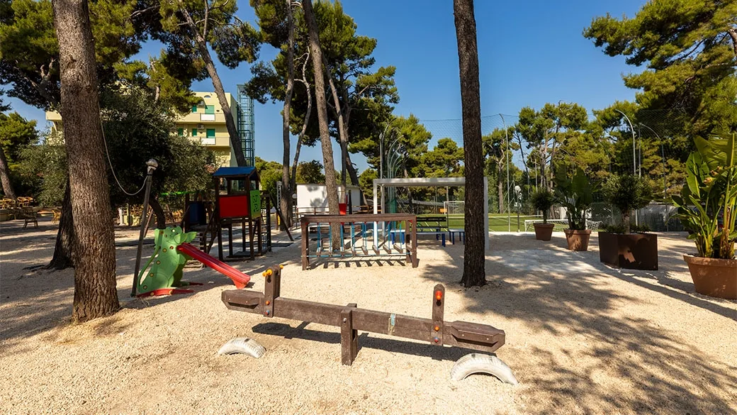 Area giochi per bambini con scivoli e altalene nel parco alberato