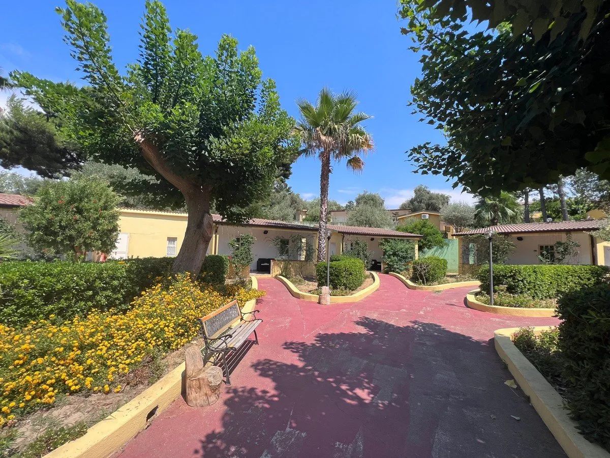 Vialetto rosso del resort con panchina, fiori e bungalow tra il verde