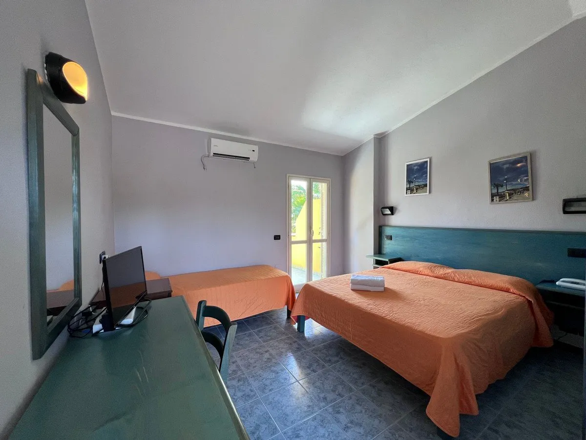 Camera con letto matrimoniale e singolo, copriletto arancione e TV
