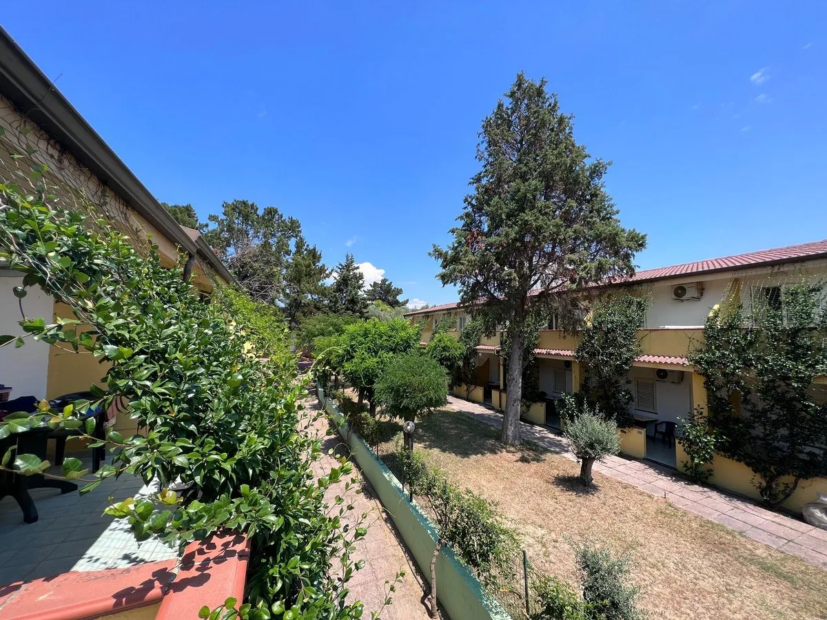 Vista dall'alto su bungalow gialli del resort tra alberi e giardini