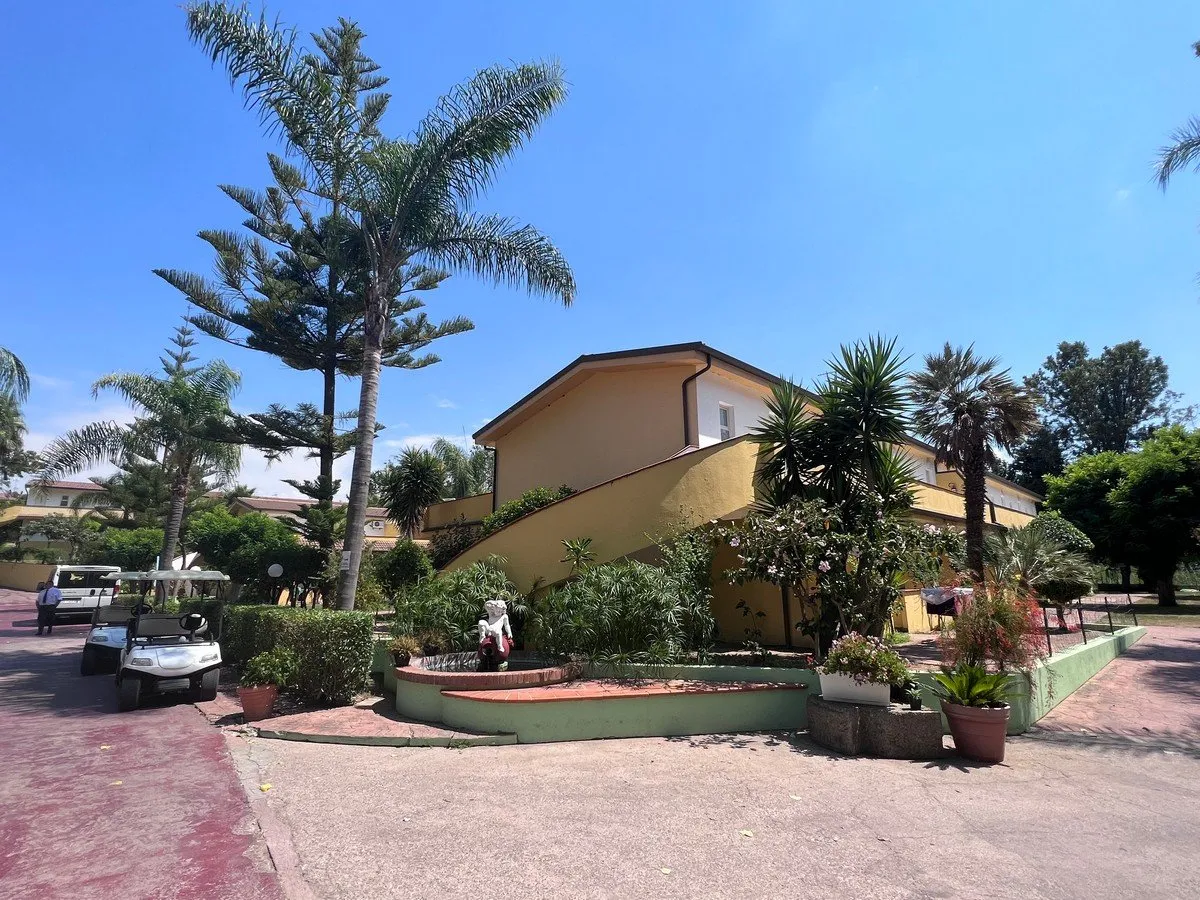 Viale del resort con palme, edificio giallo e golf cart parcheggiate