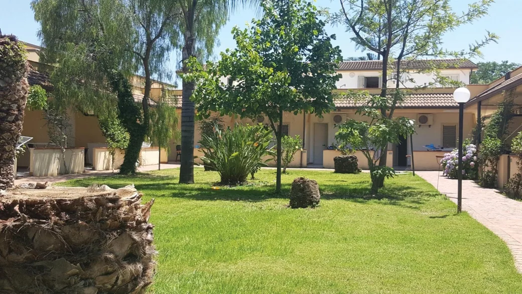 Giardino verde con alberi e prato curato tra gli edifici del resort